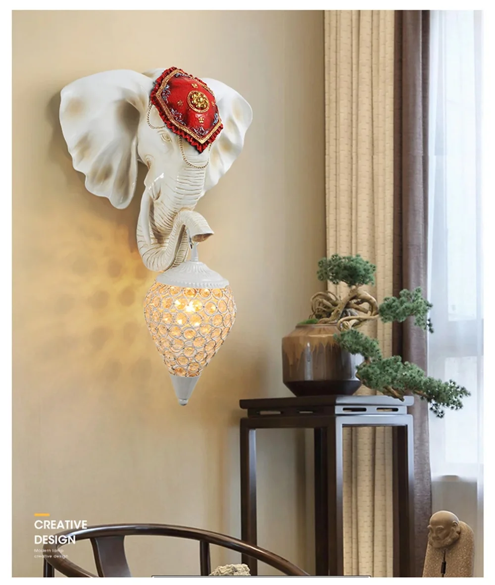 The 3D Elephant Wall Light, with its red cap and honeycomb-patterned fixture, creates a unique ambiance on the beige wall near a table adorned with potted plants.