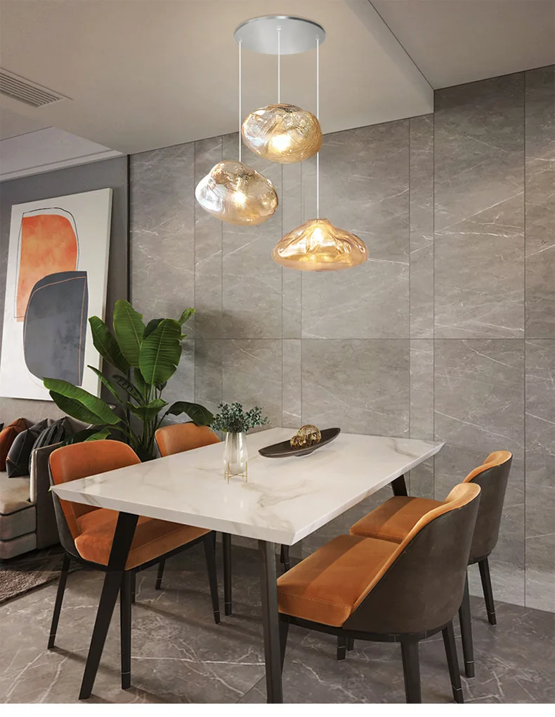 Modern dining area with a white marble table, four brown and beige chairs, abstract wall art, potted plant, and sculptural Luxe Cloud Glass Pendant Light accented with textured glass lighting hanging from the ceiling.