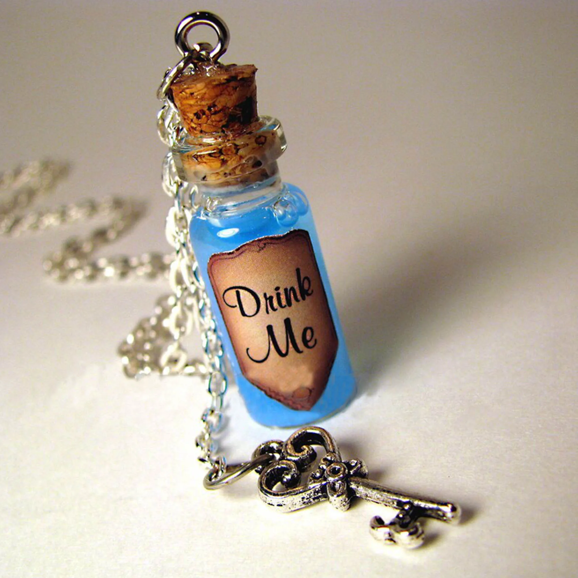 https://ae01.alicdn.com/kf/S66885fe445b44f77a40d15a9e9ffb235O/Drink-Me-Bottle-Necklace-Alice-s-Adventures-in-Wonderland-Drink-Me-Blue-Shimmer-Liquid-with-Key.jpg