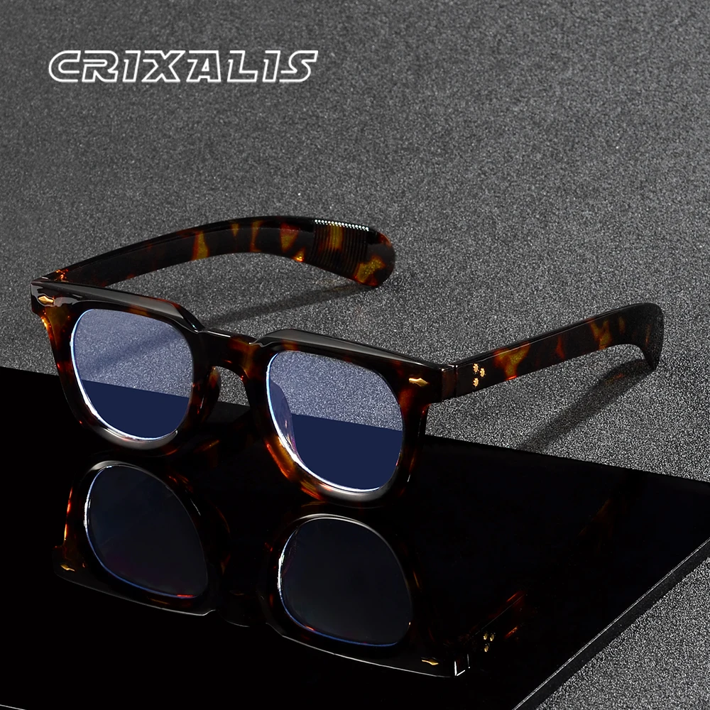 Un paio di Occhiali anti luce blu Unisex wayfarer retrò vintage con lenti colorate di blu è visualizzato su una superficie nera riflettente. Il marchio PACOSHOP24.COM compare nell'angolo superiore sinistro.