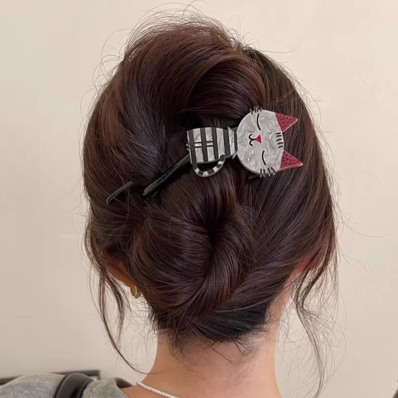 A woman with brown hair wears The Acrylic Cat Hairpin by KittyNook Cat Co., viewed from behind.