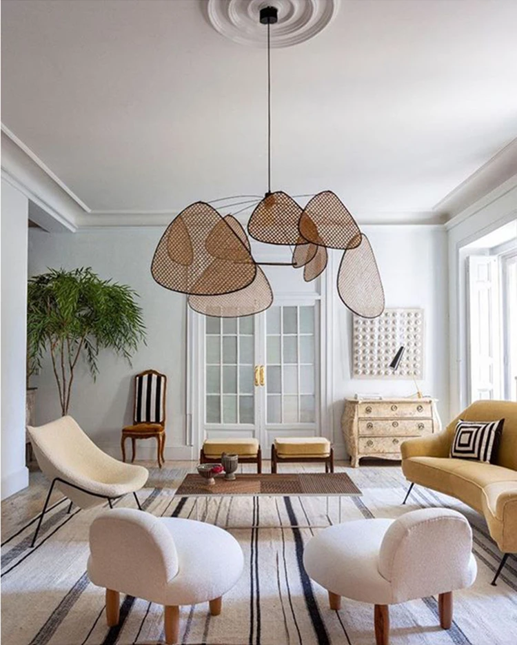 A modern living room with organic touches, featuring a rug, chairs, and a wicker chandelier.