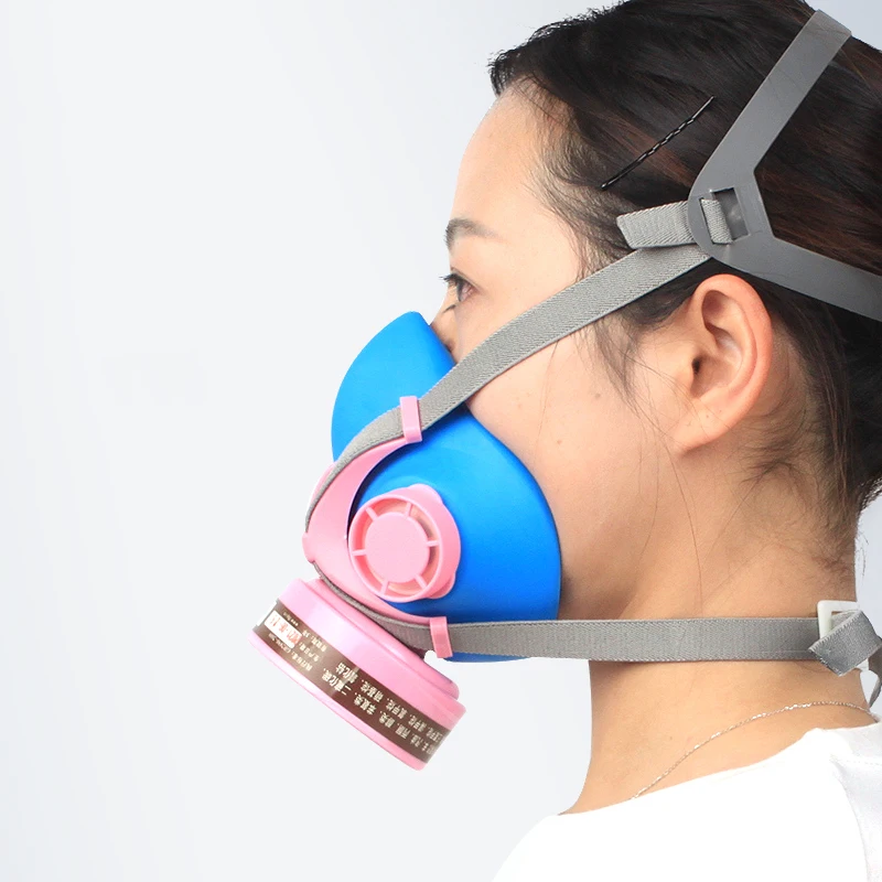 Demi-masque de protection respiratoire avec cartouches filtrantes, porté par une personne dans un atelier de peinture.