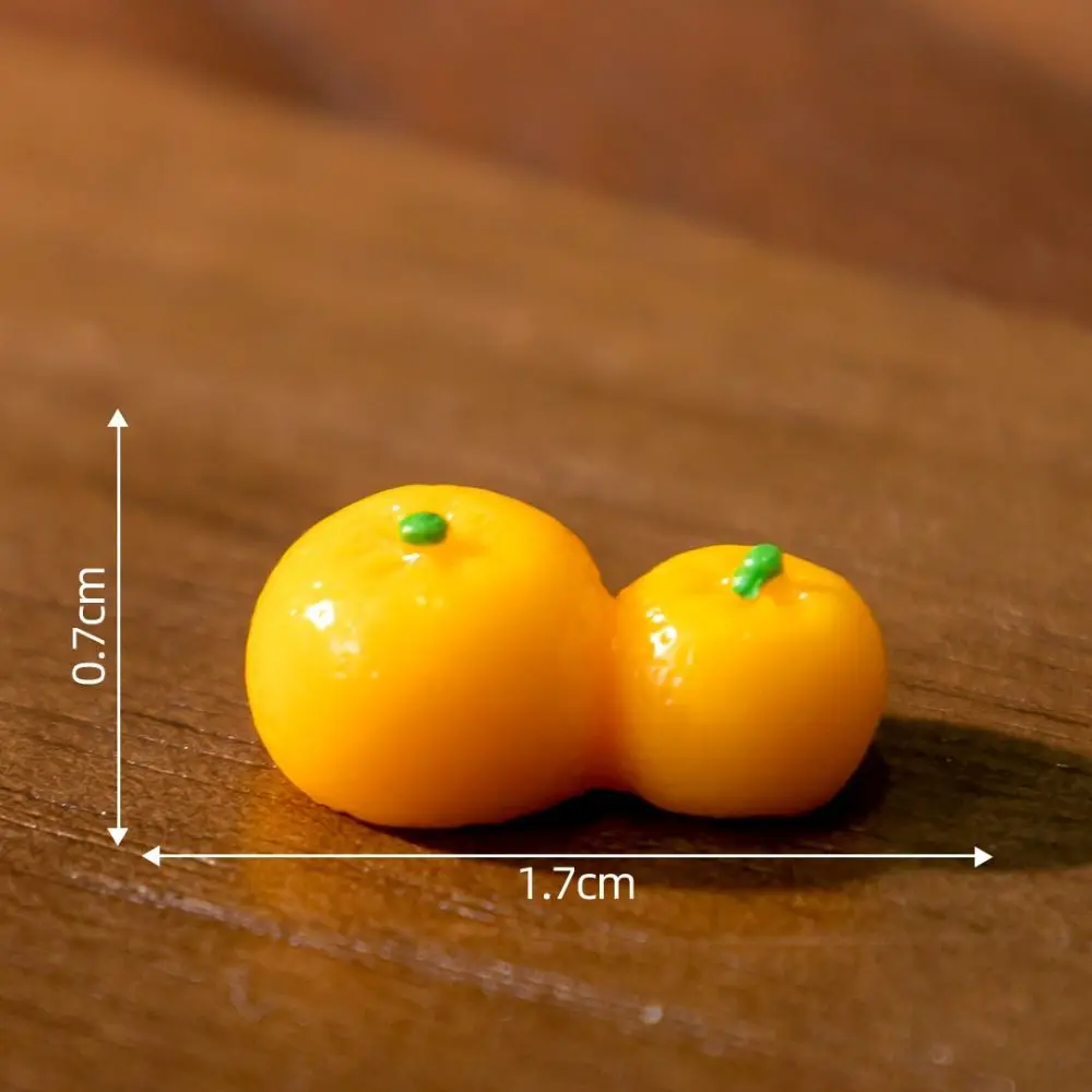 Two small orange fruits are beside a KittyNook Cat Co. Creative Cat Doll Car Ornament on a wooden surface.