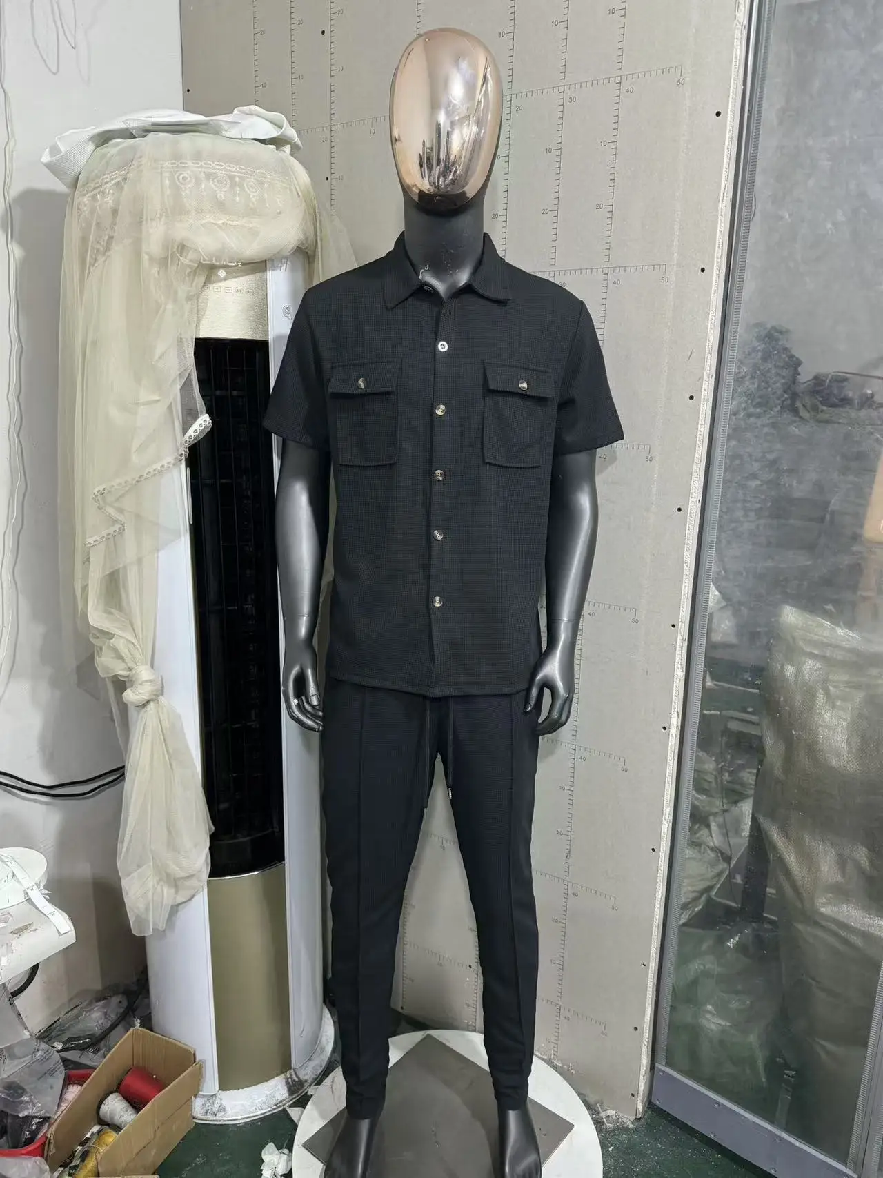 Men’s solid color waffle check short sleeve shirt and trousers two-piece set displayed on model in outdoor travel setting black