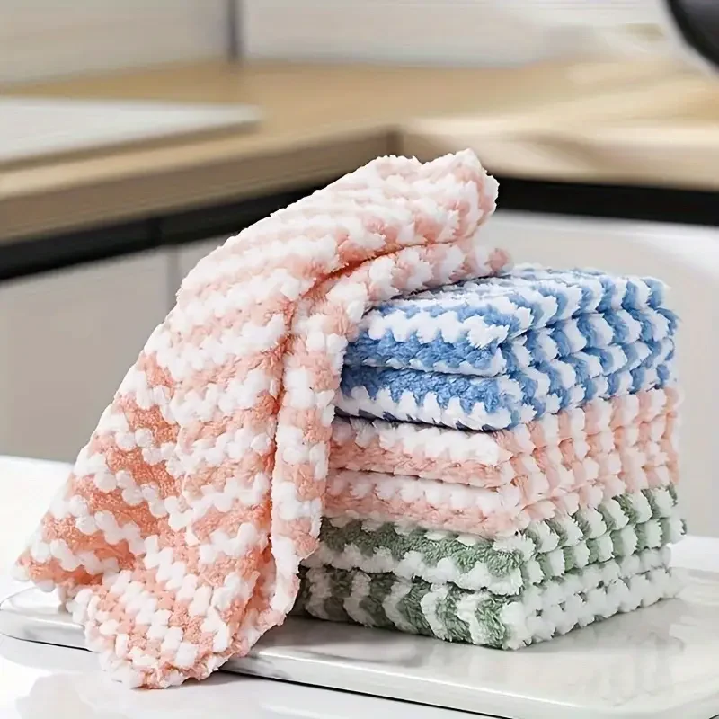 Stack of coral velvet wave-pattern kitchen wipes in assorted colors, placed beside a spray bottle and sponge on a clean countertop several