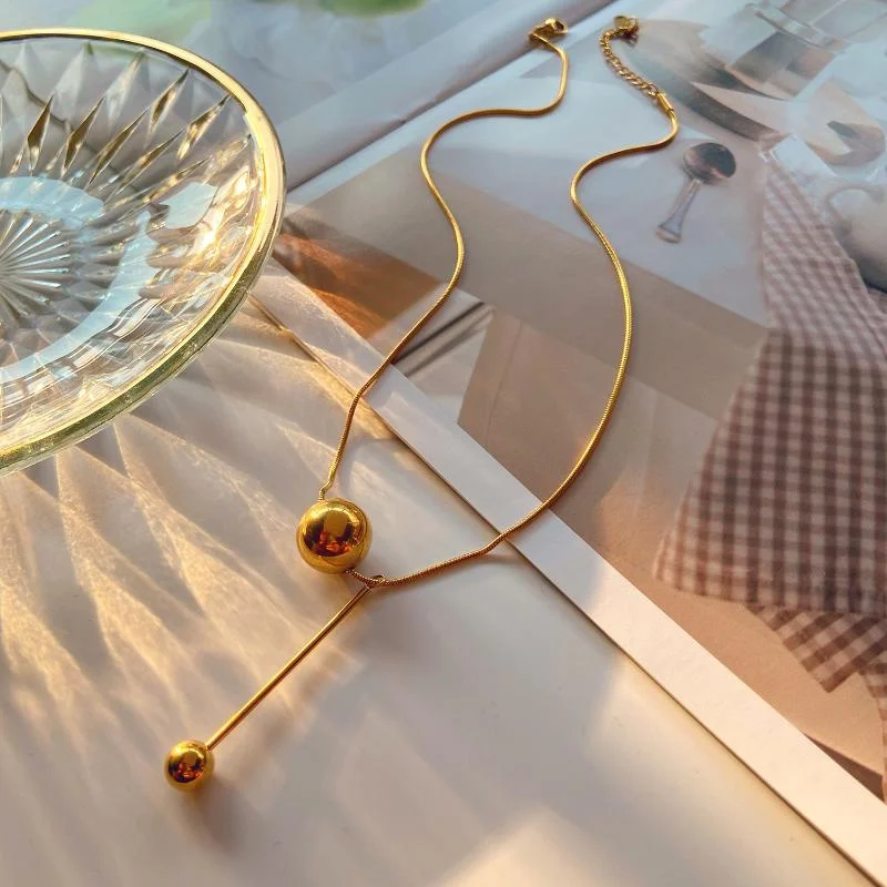 Realza tu estilo con nuestro collar de borlas de acero inoxidable. Luce un colgante de bola geométrica único y detalles de circonitas, perfecto para cualquier ocasión.