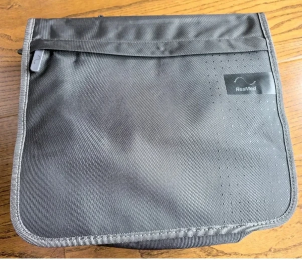 Vue de dessus du sac de transport ResMed AirSense 10 CPAP, avec sa poche avant zippée et sa bandoulière amovible.