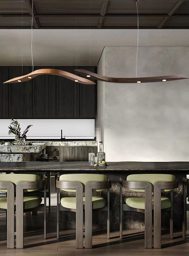 Modern kitchen featuring a marble island, green cushioned stools, dark cabinetry, and a stylish Spiral Wood Pendant Light hanging above the counter for an Organic Modern Lighting accent.
