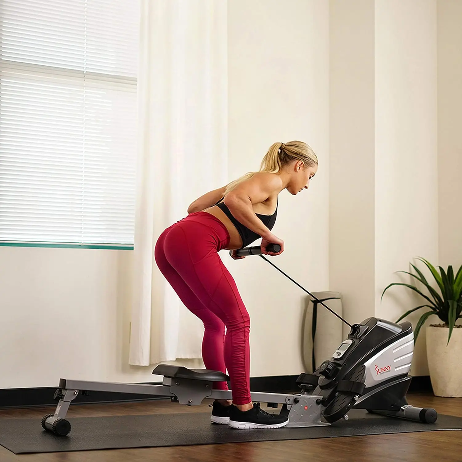 A woman working out with a sunny magnetic rowing machine sold by 100 Spartans