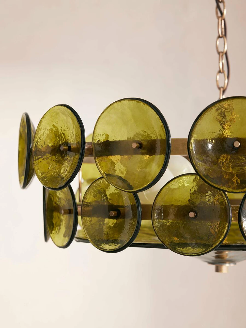 A close-up of the Italian Retro Pendant Light showcases round, translucent green glass discs elegantly attached to a sleek metal frame.