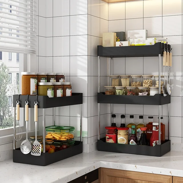 A 3-tier countertop spice rack organizer in black, neatly holding various spice jars, oil bottles, and hanging kitchen utensils.