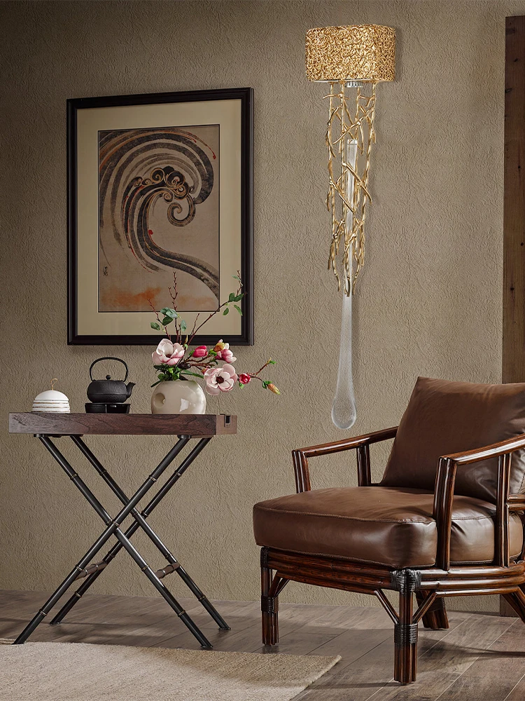 Elegant room with a brown leather chair, a small table holding a tea set and flowers, and framed artwork on the wall. The Luxury Vertical Wall Light casts a warm glow, enhancing the scene’s graceful charm.