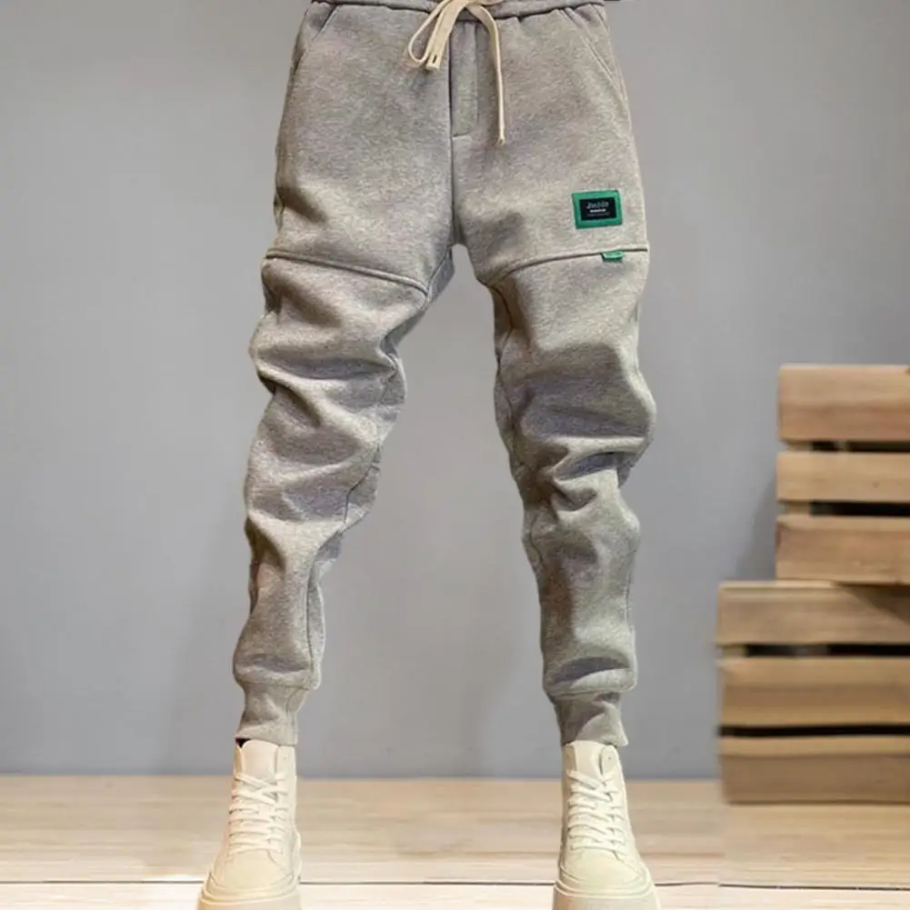 

Men Solid Color Pants Men's Fall Winter Drawstring Pants with Plush Lining Ankle-banded Pockets Patchwork Badge Detail Cozy