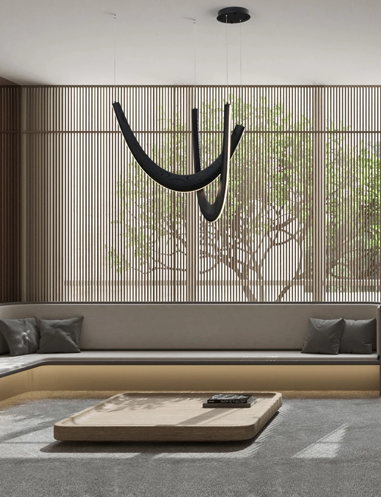 Minimalist living room with built-in beige seating, gray cushions, a low rectangular coffee table, slatted wood wall panels, large window, and a sculptural Double Curve Wood Pendant Light.