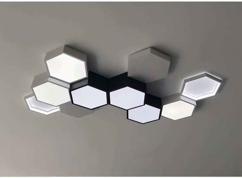 A modern ceiling light fixture with adjustable hexagonal shades in white and gray tones, displaying both lit and unlit sections.