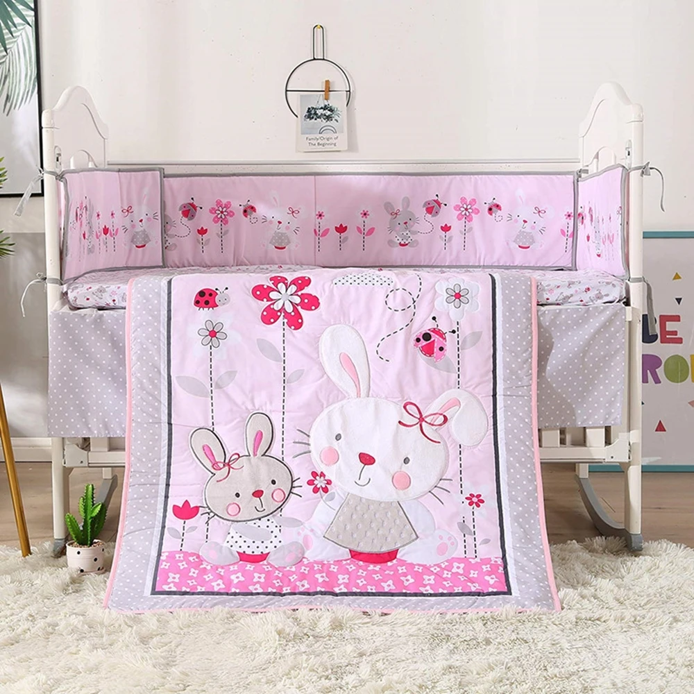 Tour de lit bébé fille rose avec motifs floraux et couette assortie dans un lit bébé