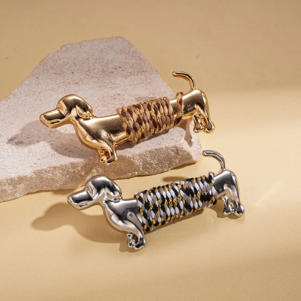 Polished gold and silver luxury sausage dog lapel brooch pins styled on a black wool blazer collar and a white business suit next to a size dimension chart