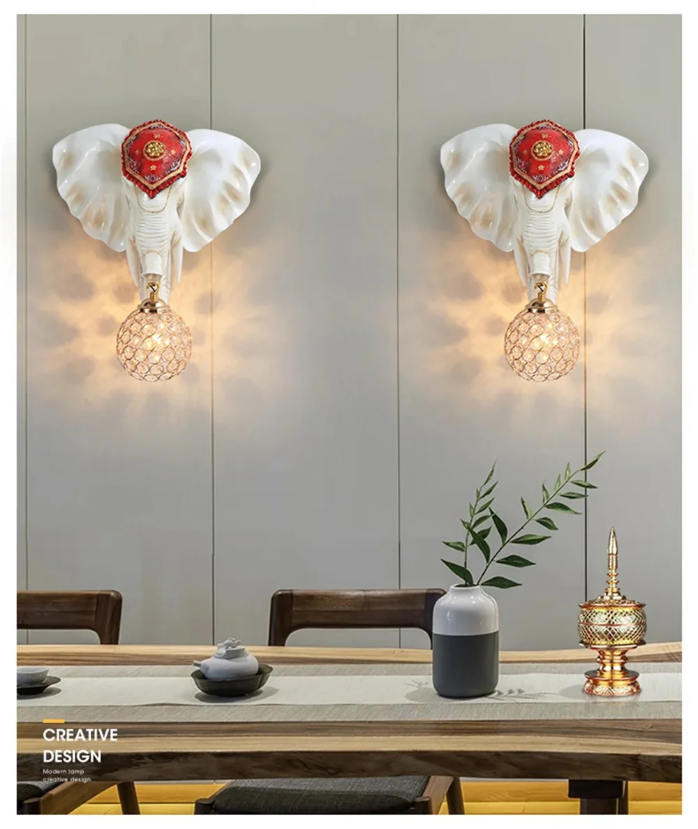 Two 3D Elephant Wall Lights with red accents add a distinctive ambiance to a room. Below, a table displays decorative items such as a green-leaf vase and a golden container.