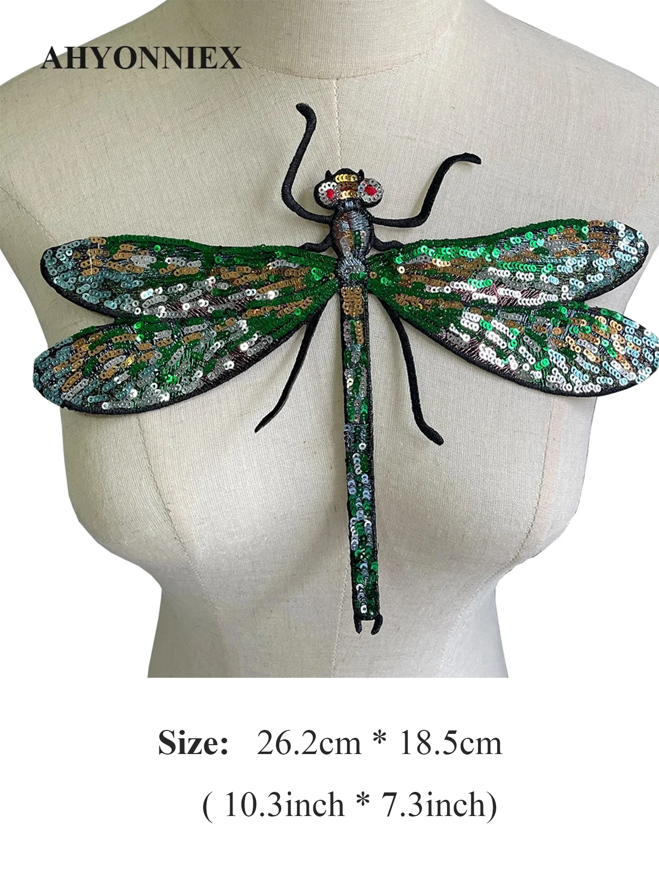 Suur pealetriigitav kiil, sädelevate roheliste ja kuldsete litritega, paigutatud neutraalsele mannekeenile.