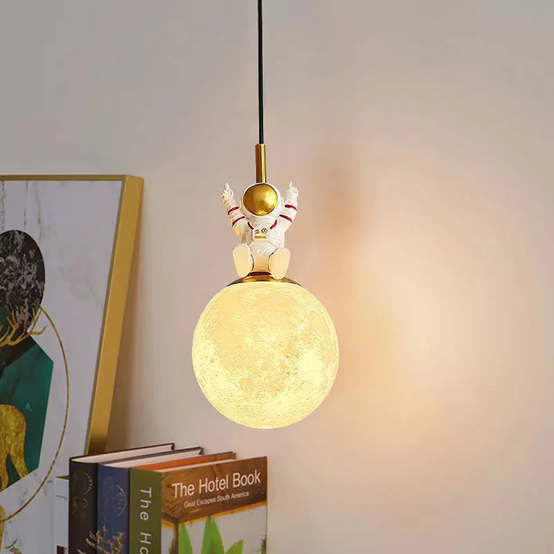 A creatively designed pendant light featuring an astronaut gracefully floating above a moon.