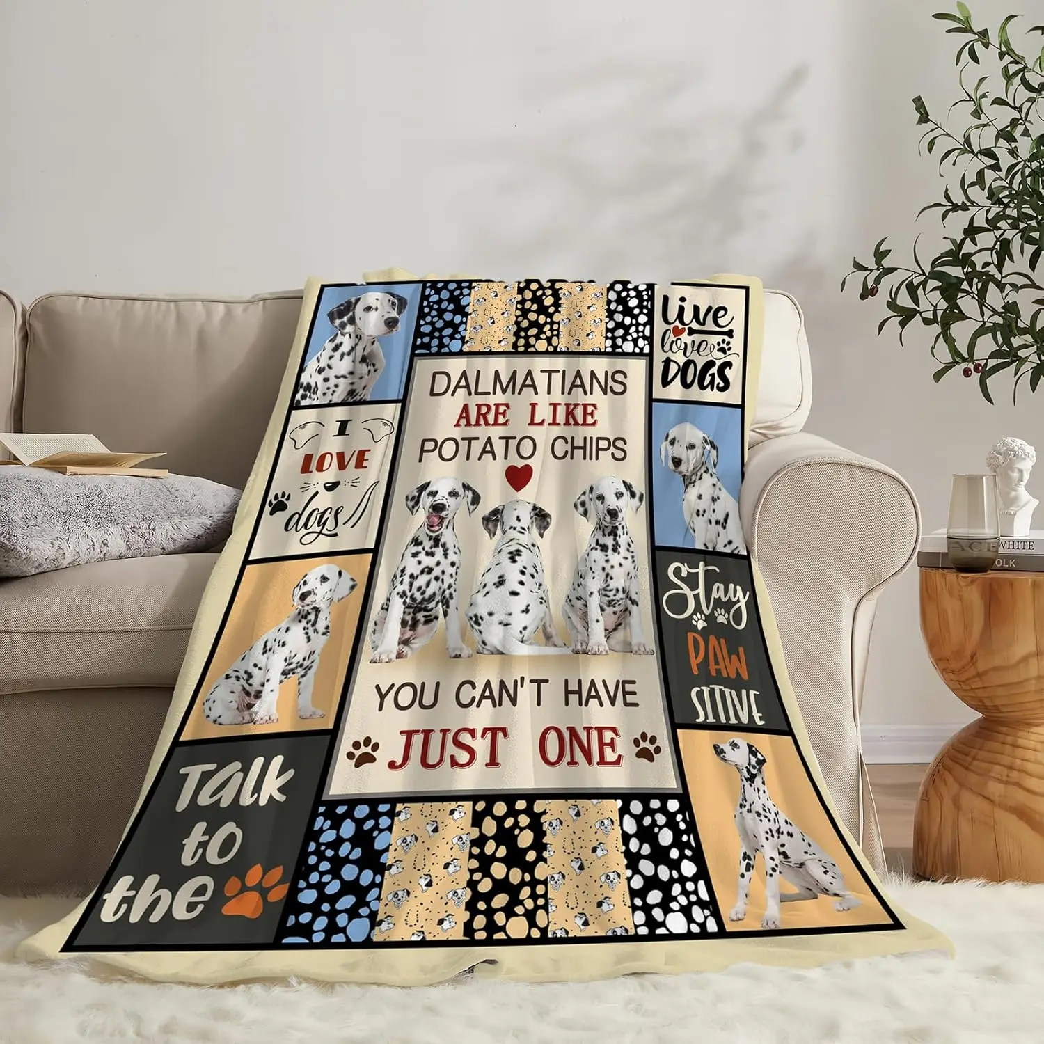 A cozy patchwork flannel fleece throw blanket with a funny Dalmatian dog print displayed over a living room sofa.