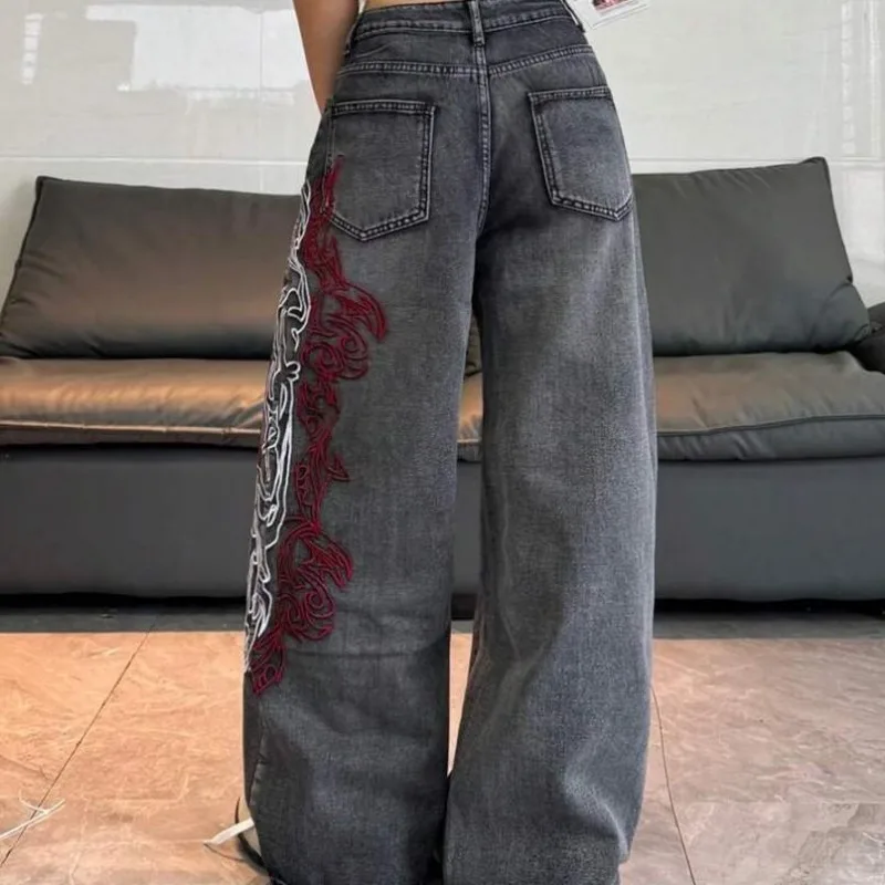 Jean vintage gris foncé délavé pour femme, taille haute, coupe large, avec broderie abstraite rouge et blanche sur le côté, en denim, collection été 2026, style streetwear européen