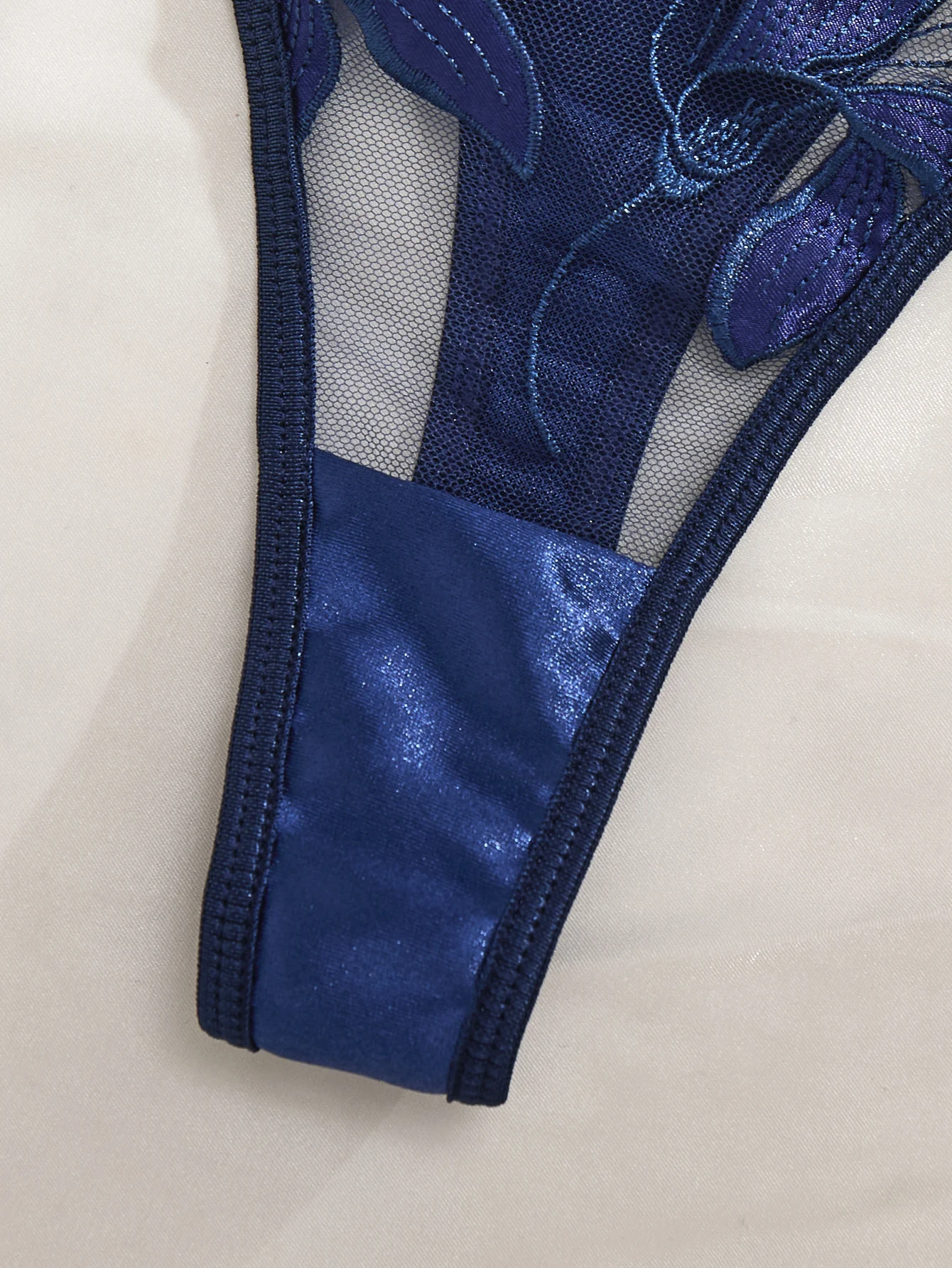 Matching thong detail with blue embroidery, sheer mesh, and slim strap design