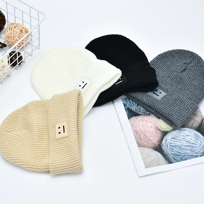 Cream-colored ribbed knit beanie hat for men featuring a small square patch with a simple smiley face perfect for men’s winter wear.