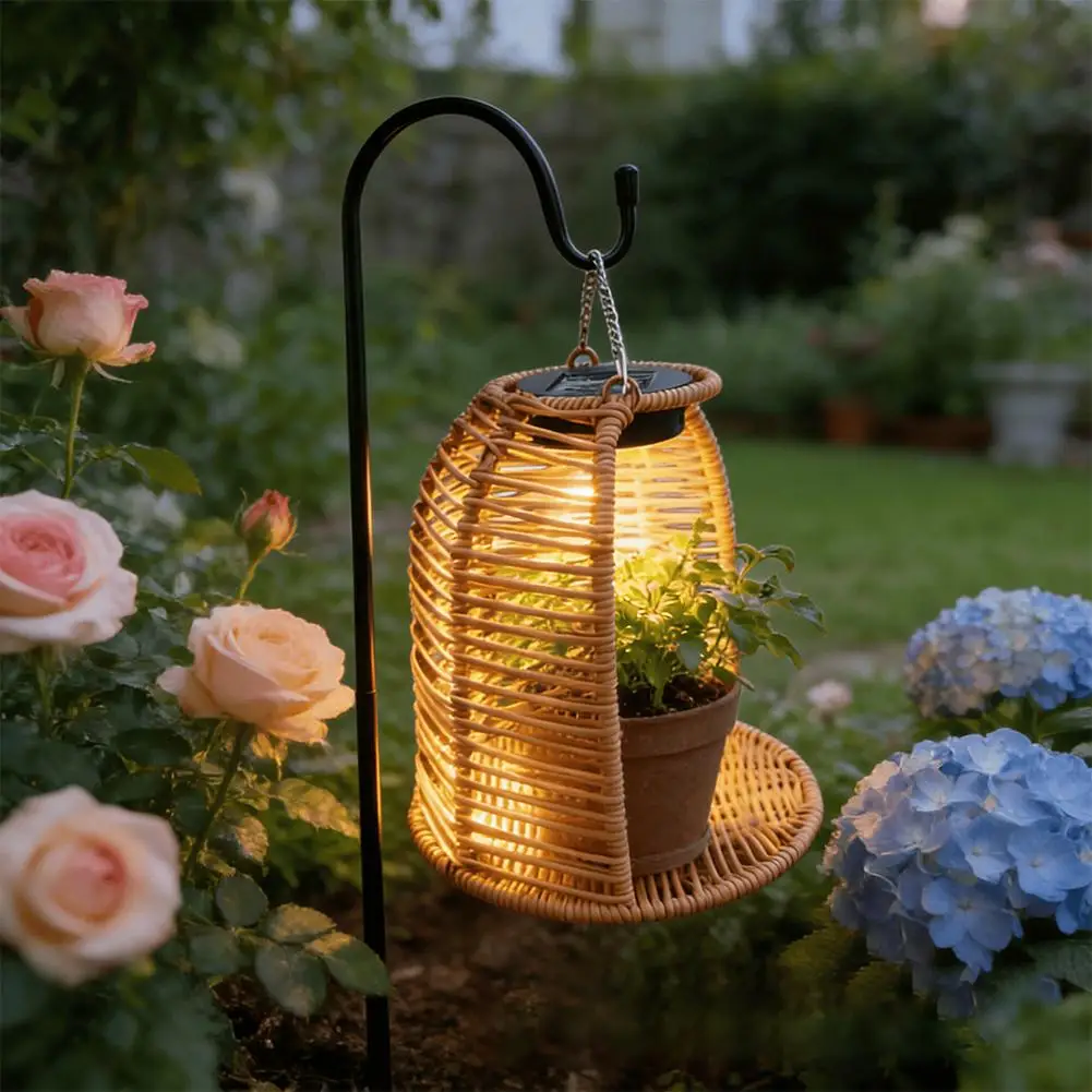 Rattan solar lantern hanging from shepherd's hook beside outdoor seating