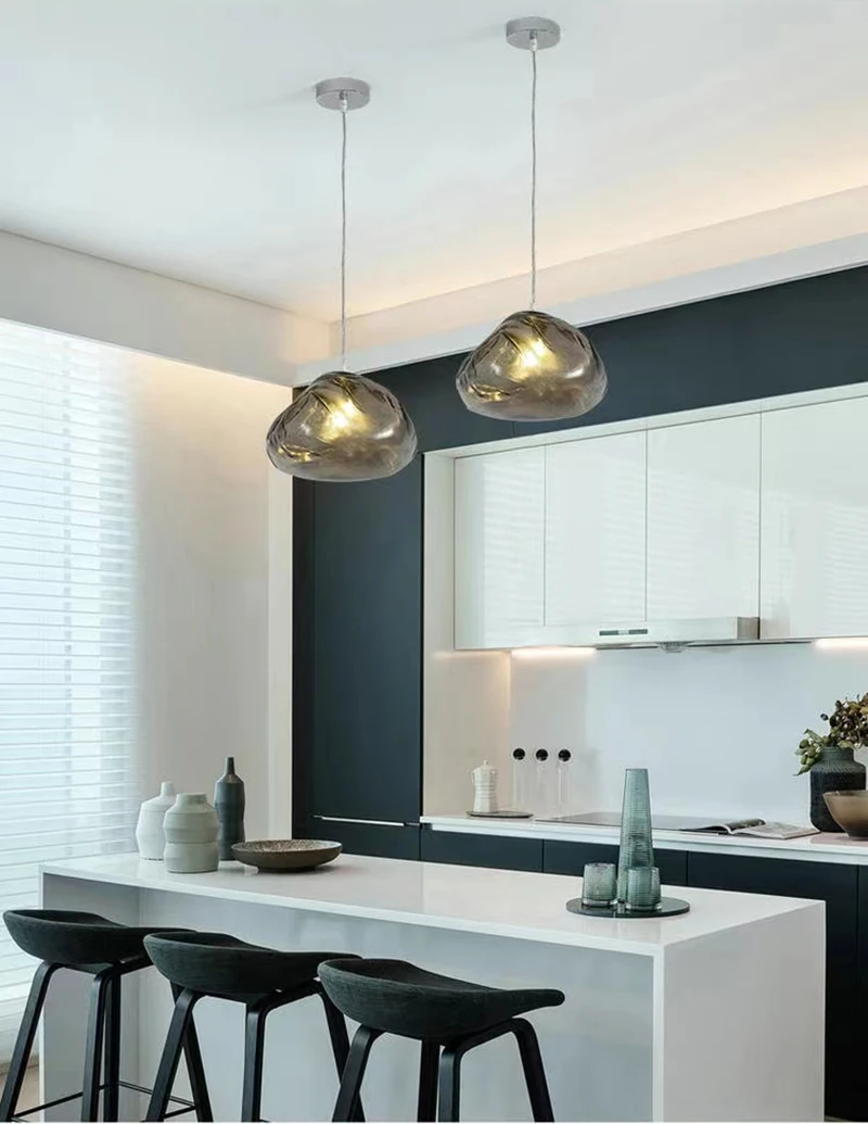 Modern kitchen with a white island, three dark stools, decorative vases, and a sculptural Luxe Cloud Glass Pendant Light paired with textured glass lighting for a stylish, contemporary touch.