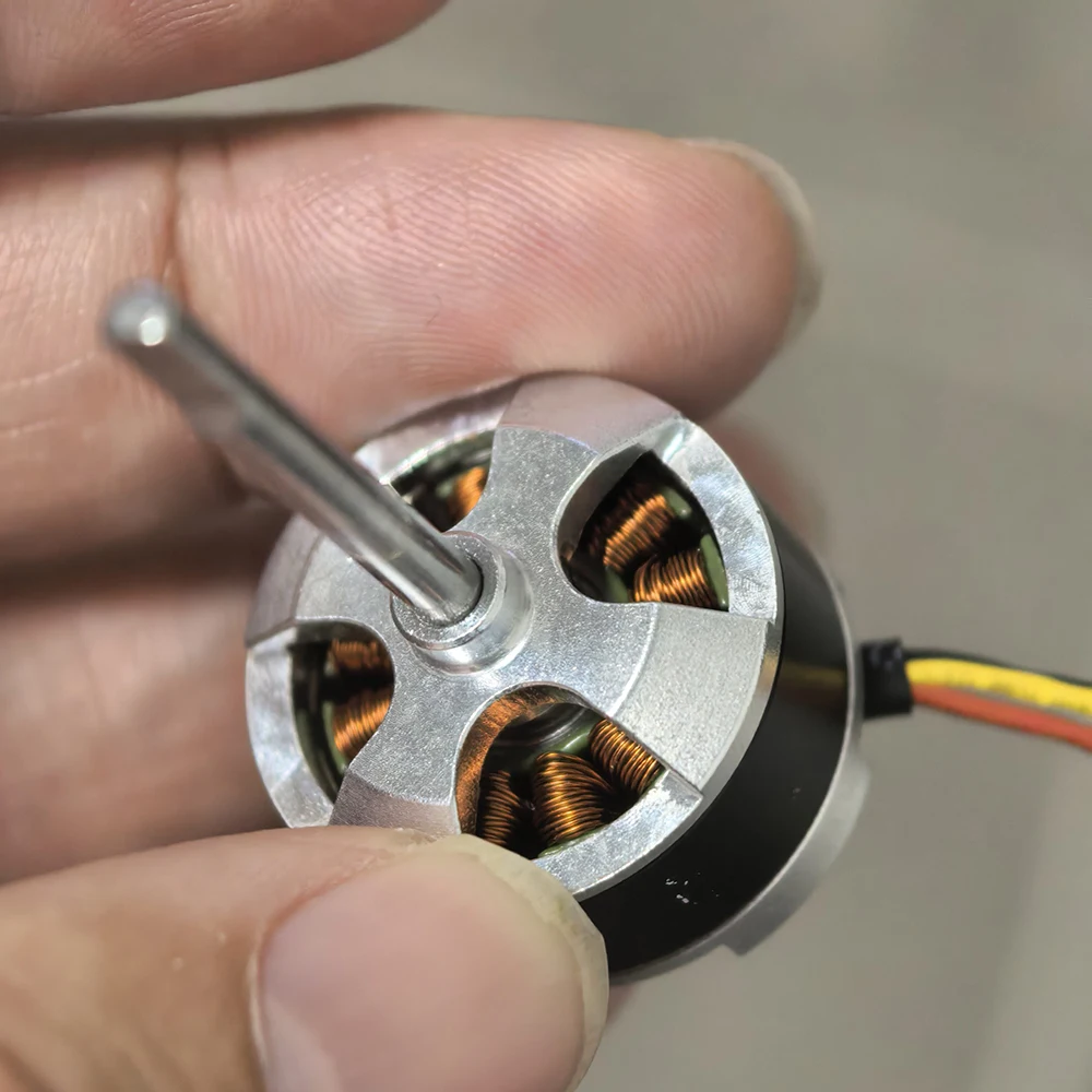 Moteur BLDC 23mm 1700KV pour modèle d'avion posé sur une surface, avec une pièce de monnaie pour l'échelle.