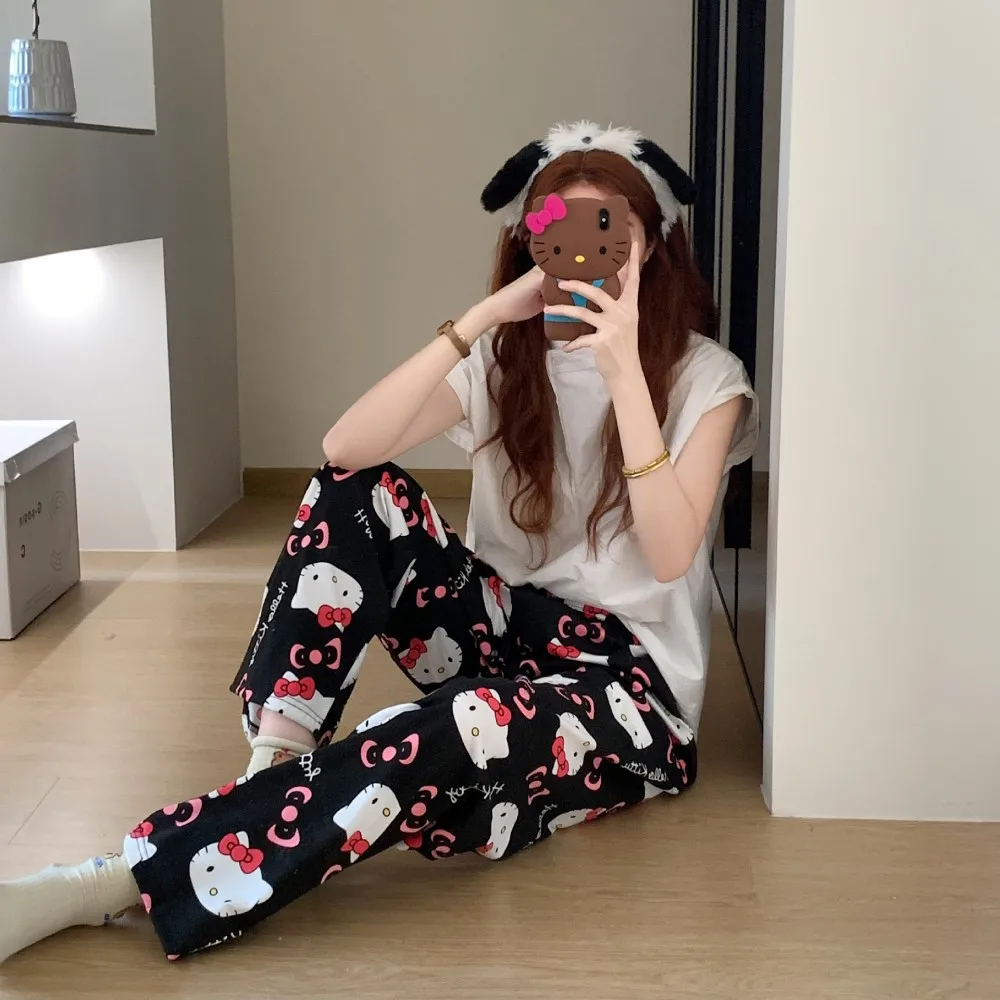 A pair of loose-fitting Hello Kitty pajama pants with a charming cartoon print black+