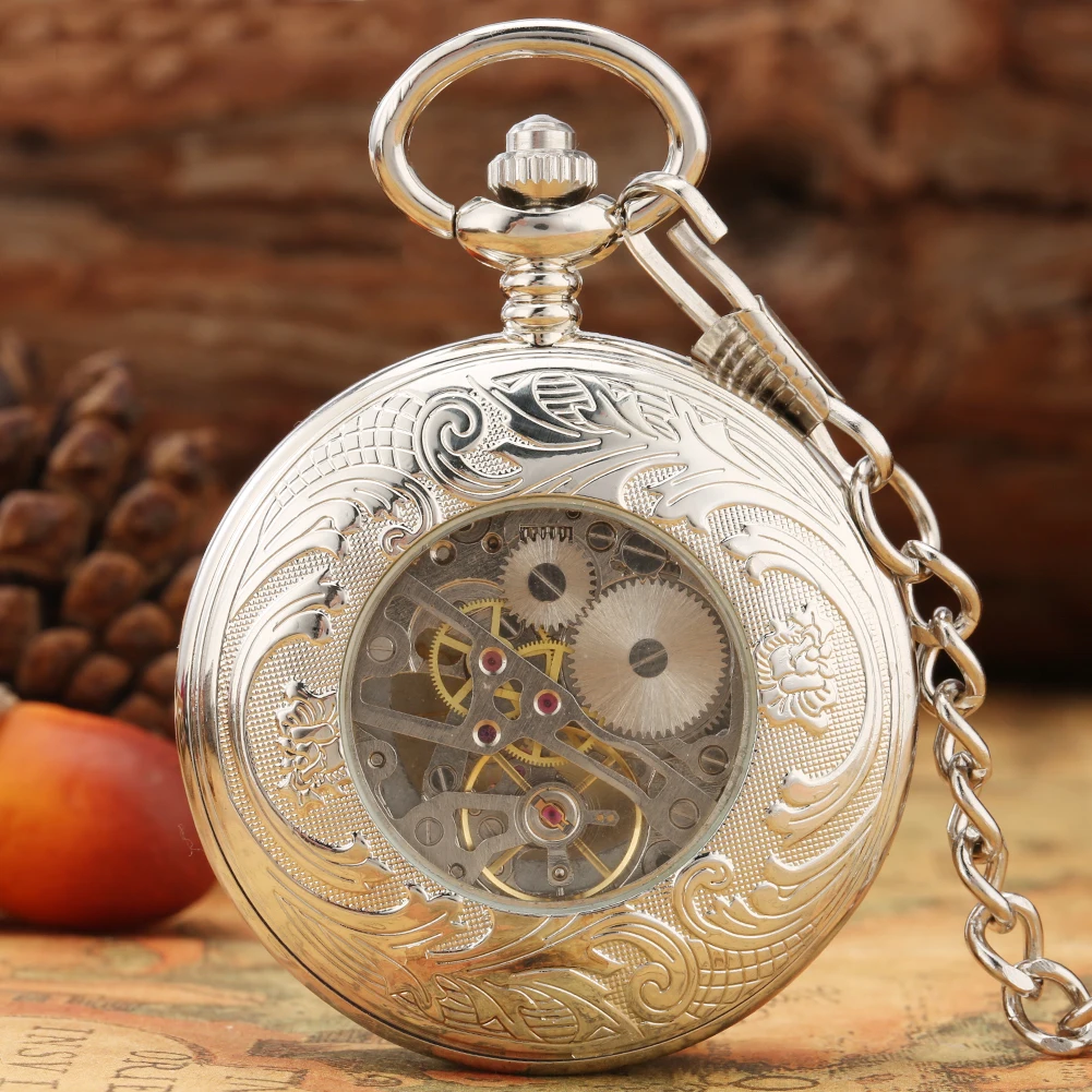 The Silvery Pocket Watch, featuring ornate engravings and a skeleton dial, rests on a surface with its chain draped nearby, accompanied by a pinecone and fruit.