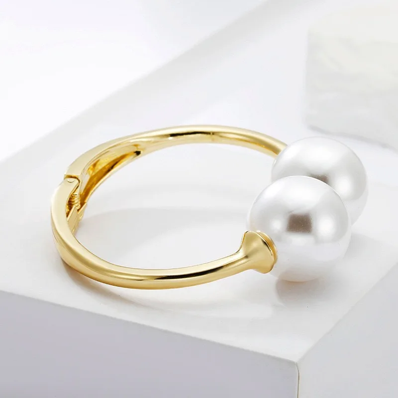 Gold-tone cuff bracelet with pearl ends for women – wide statement bangle with modern fashion appeal.