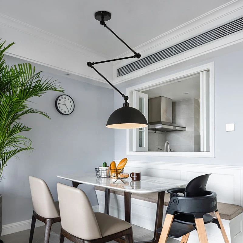 A modern dining area showcases a marble table and beige chairs, highlighted by a striking Zig Zag Pendant Light. The industrial vibe is enhanced with a black wall clock and high chair. An open kitchen window reveals a potted plant adding greenery to the corner.