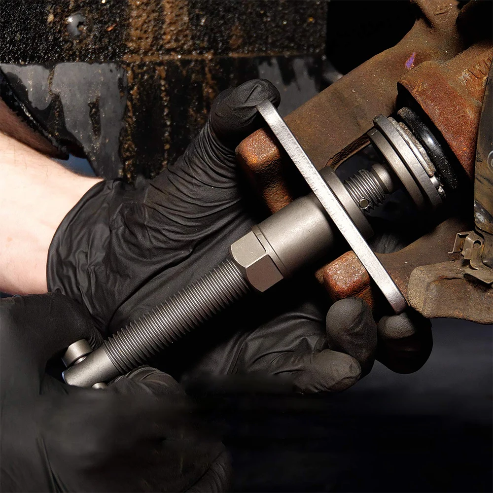 Mechanic using brake caliper tool on a vehicle