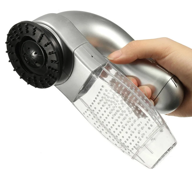 Close-up of a person holding an ergonomic silver pet vacuum groomer at an angle, highlighting the transparent fur storage chamber and massage bristles.