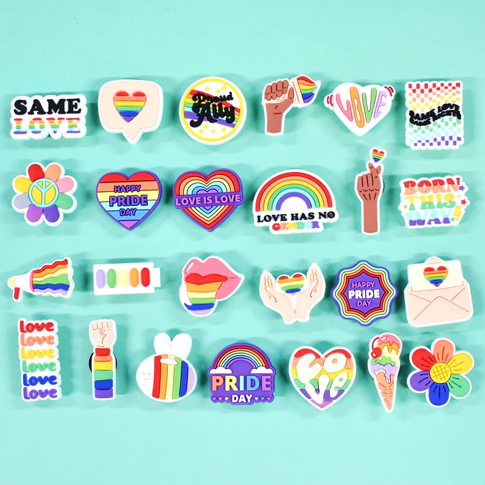 Collection of colorful Pride-themed shoe charms on a light blue background