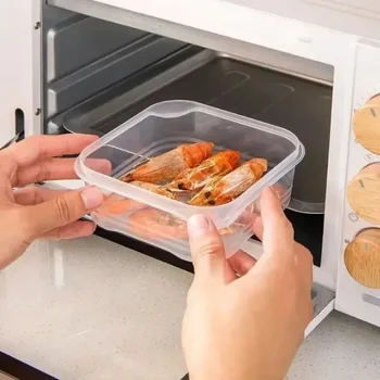 A stack of clear, flat freezer storage containers inside a freezer drawer, neatly organizing portions of meat and chopped vegetables.
