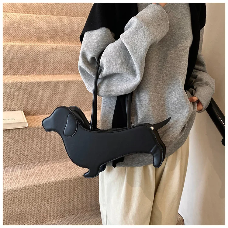 Model wearing a black three dimensional dachshund shaped PU leather shoulder bag