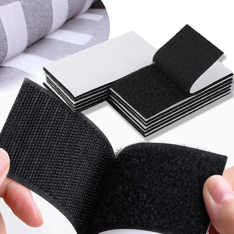 Black Velcro strips on a white surface with hands holding one strip.