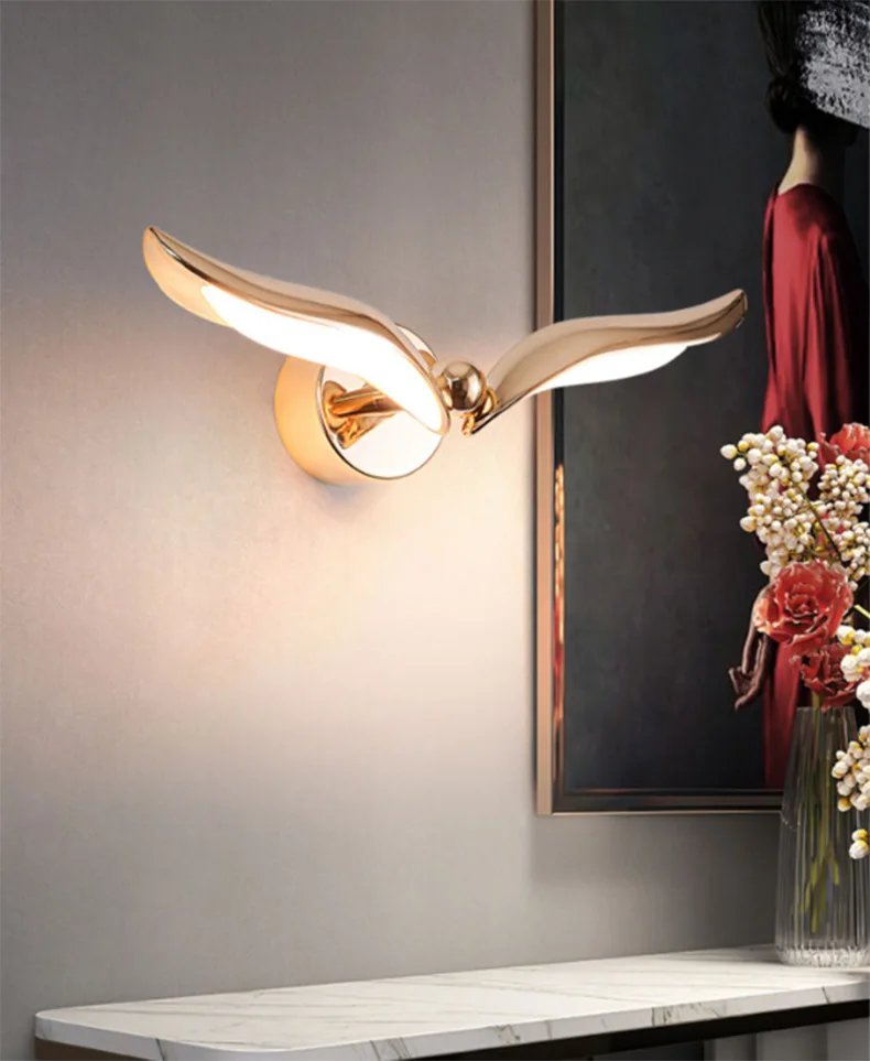 A transformable gold wing-shaped wall light, perfect for adding an elegant touch to any interior space. The Flying Bird Wall Light can be placed on a table or mounted on a wall to illuminate