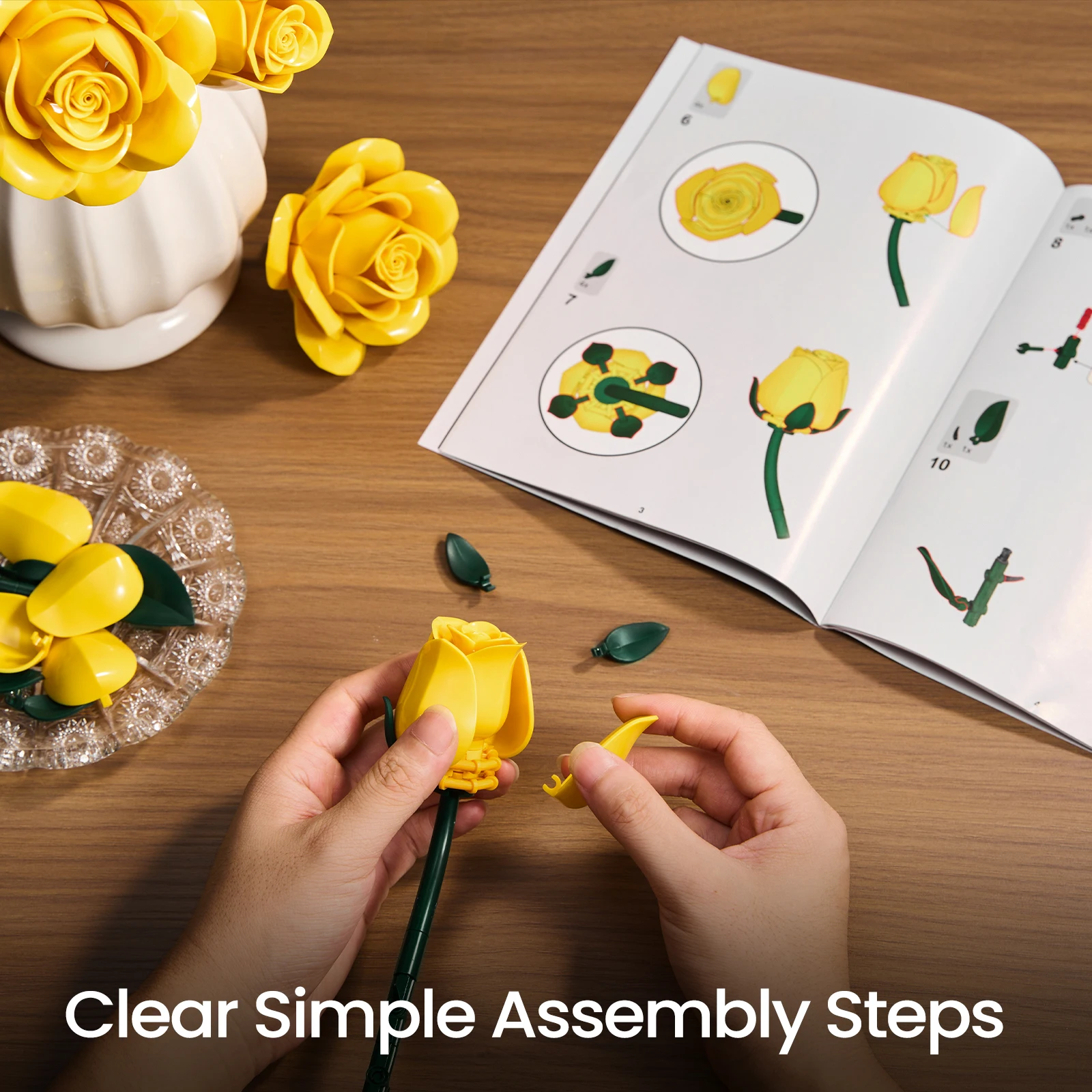 Hands assembling yellow rose building blocks with instruction manual