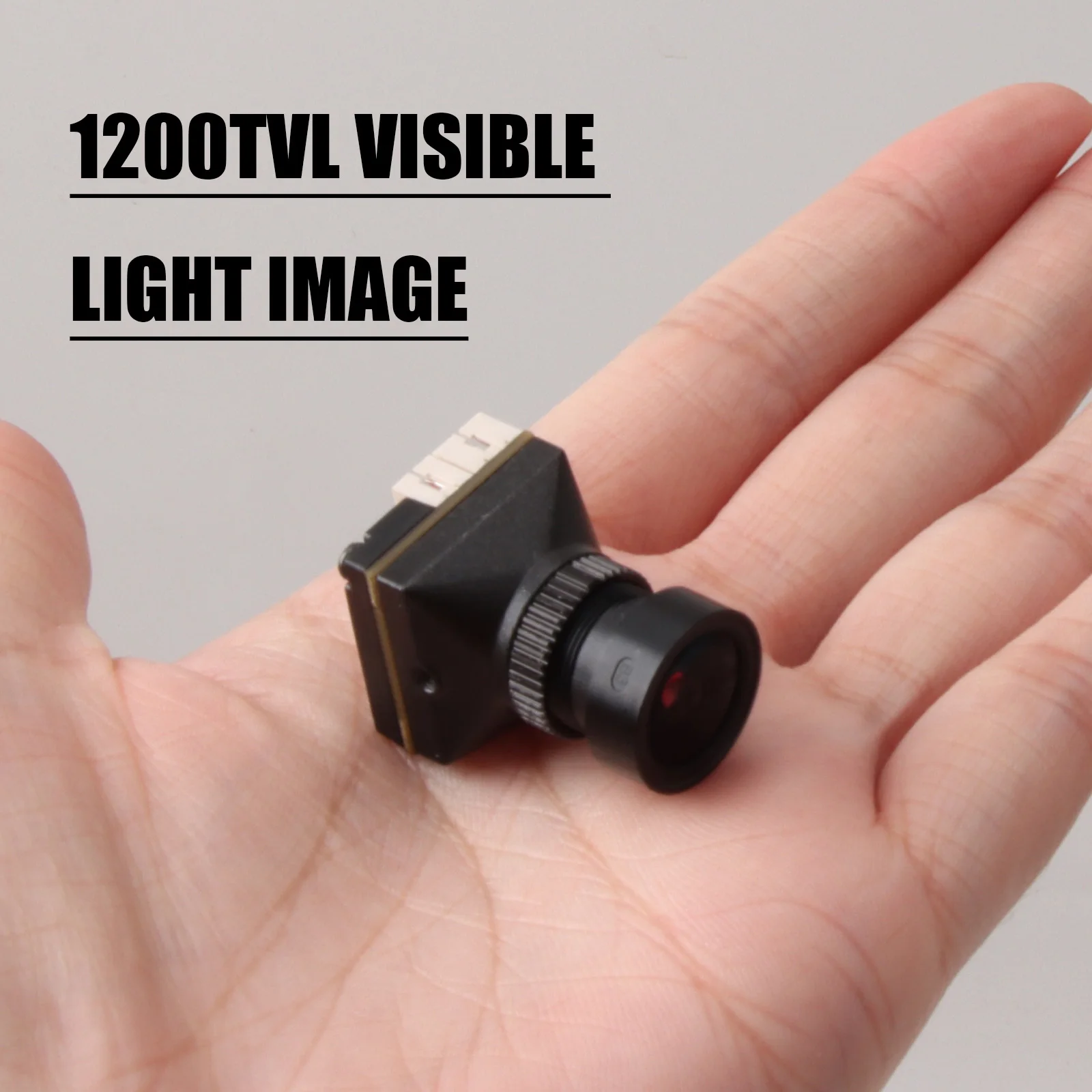 Caméra FPV 1500TVL CMOS 1/4.5" 19x19mm pour Drone de Course posée sur une surface, avec câbles déroulés.