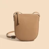 2948-cf3016.jpg A woman wearing a genuine leather crossbody bag, showcasing its compact size and adjustable strap.