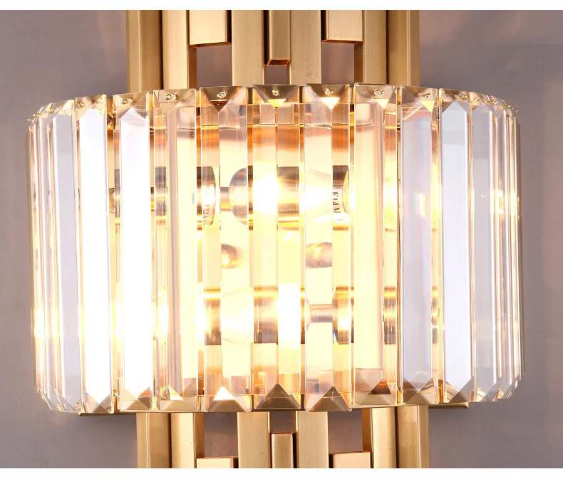 The Luxury Geometric Wall Sconce, featuring an Art Deco design with a gold frame and vertical crystal rods, elegantly encases two lit bulbs, ideal for enhancing your sophisticated home decor.