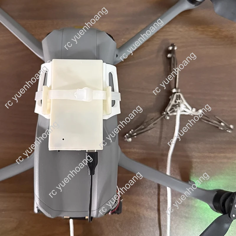 Gros plan sur la pince de sauvetage pour drone, détaillant la finition en acier inoxydable et le système d'accroche.
