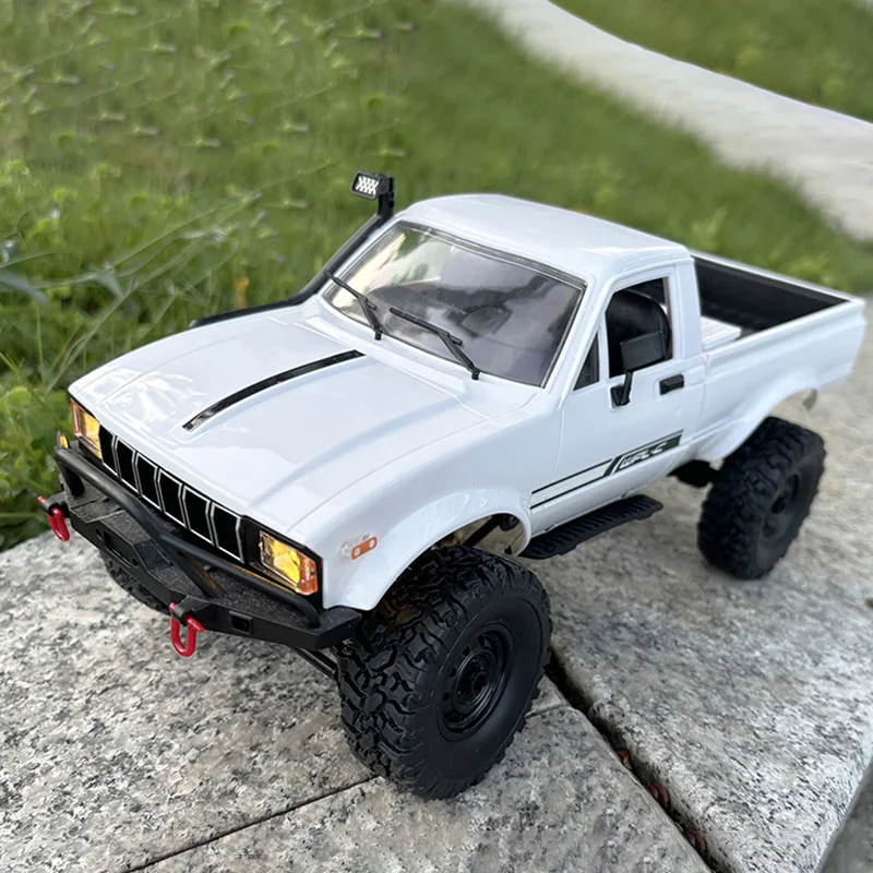 Vue de dessus de la voiture RC 4WD 1/16 C24-1 montrant son châssis et ses suspensions.
