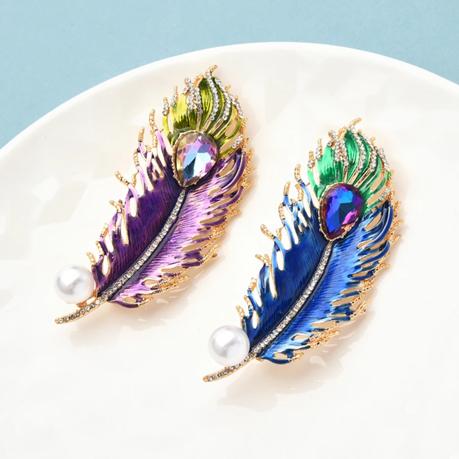 Colorful feather-shaped earrings on a white plate with a light blue background